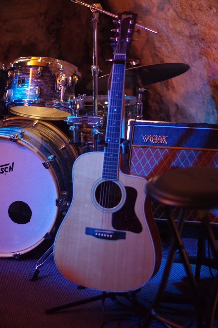 Guitare, batterie et amplificateur installés dans la cave voûtée